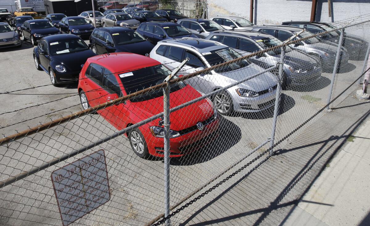 Volkswagen diesels are shown behind a security fence on a storage lot near a VW dealership in Salt Lake City.