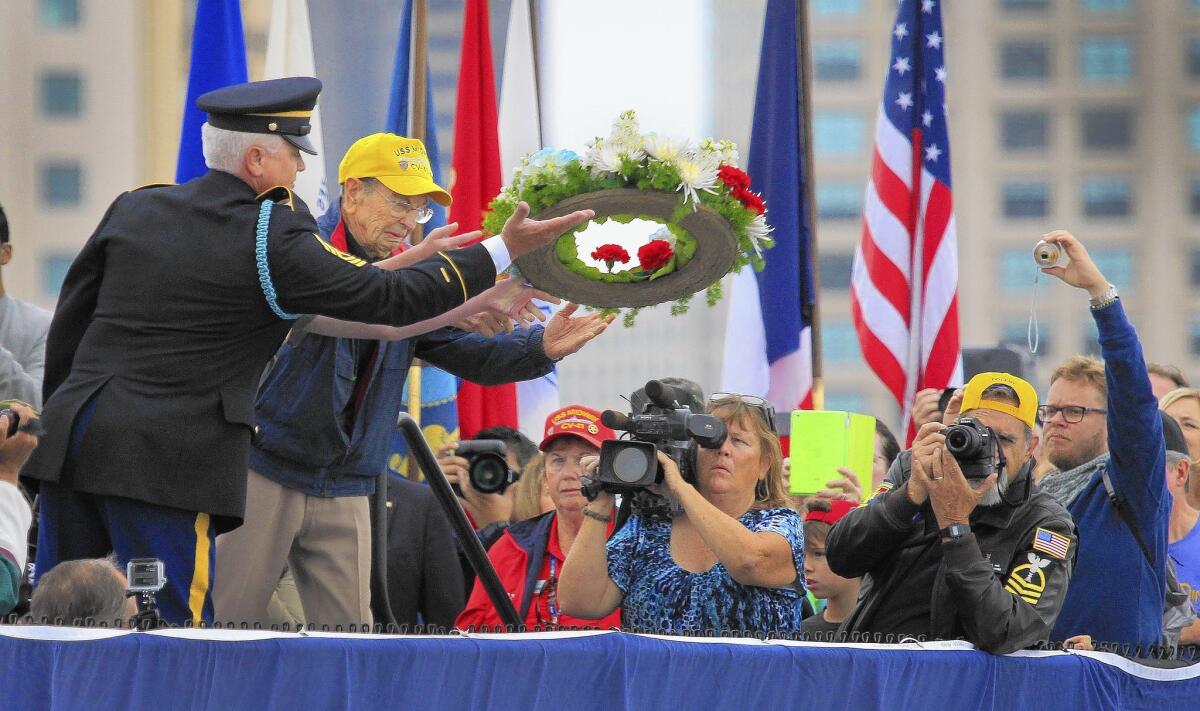 U.S. Army Command Sgt. Maj. William "Bud" McLeroy, left, and former Army Staff Sgt. Bob Thomas toss a wreath from the carrier museum Midway into San Diego Bay during a Memorial Day ceremony honoring World War II veterans.