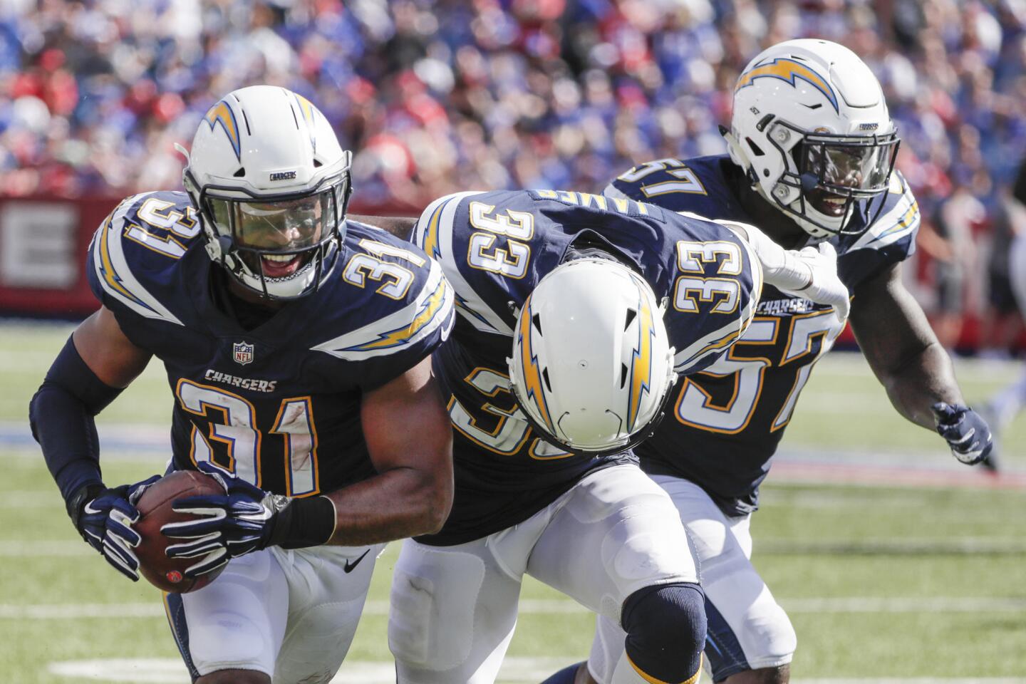 Chargers safety Adrian Phillips celebrates an interception with teammates Derwin James and Jatavis Brown at New Era Field on Sunday.