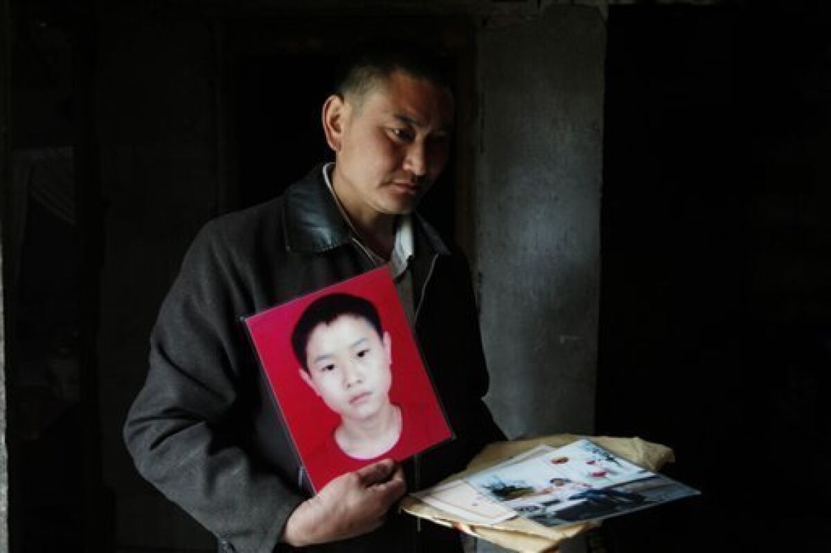 In this photo taken on April 5, 2009, Zhou Lekang 43, holds a picture of his son Zhou Jingbo who was 16 when he was killed after his middle school collapsed in the May 12, 2008 earthquake in Dujiangyan, China. The death of so many children has touched a nerve nationwide, raising questions about official corruption, mismanagement, government responsibility _ the underside of fast-paced economic growth. The political sensitivity of the issue has spawned many instances of government attempts to intimidate the parents and activists fighting to get the truth out. (AP Photo/ Elizabeth Dalziel)