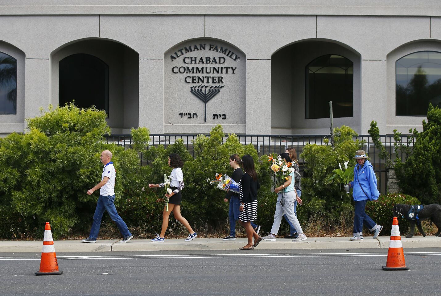Poway residents walk to leave flowers at a memorial near the Chabad of Poway, where a deadly shooting took place the day before on April 28, 2019 in Poway, California. (Photo by K.C. Alfred/The San Diego Union-Tribune)