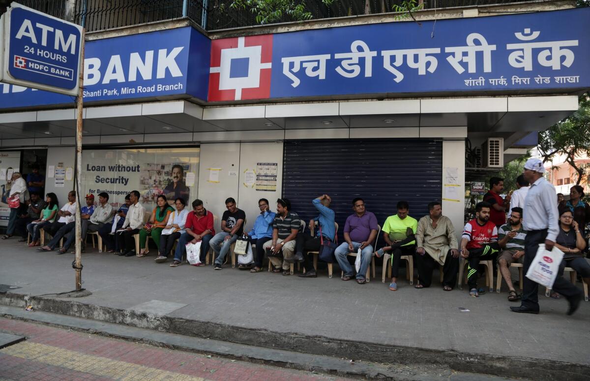 People in India wait to deposit, exchange and withdraw money outside bank branch on the outskirts of Mumbai earlier in December.