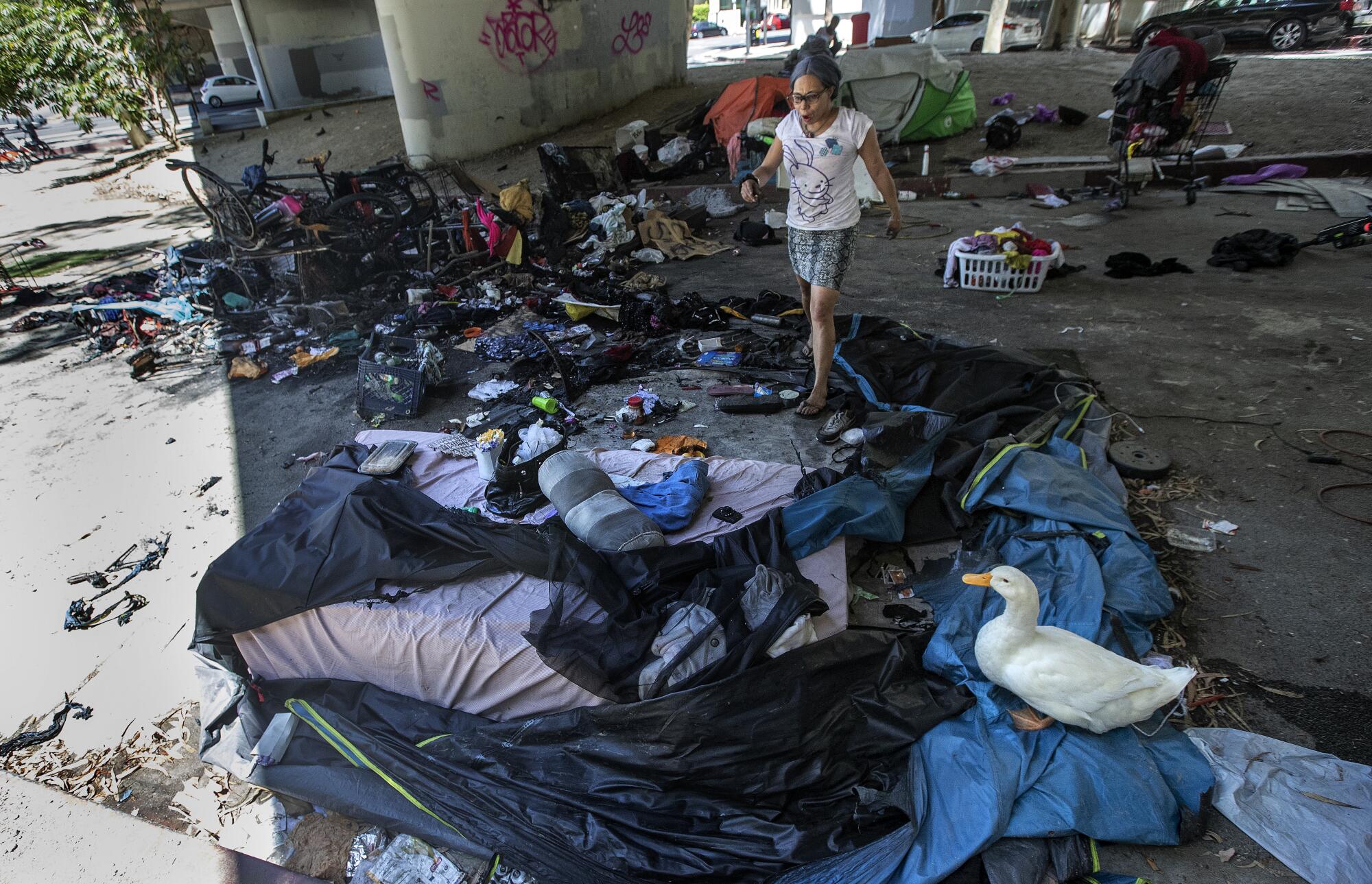 A woman walks through burned tents in downtown Los Angeles.