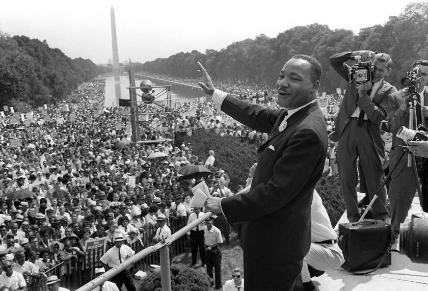 Martin Luther King waves to a massive crowd on the National Mall with the Washington Monument and Reflecting Pool