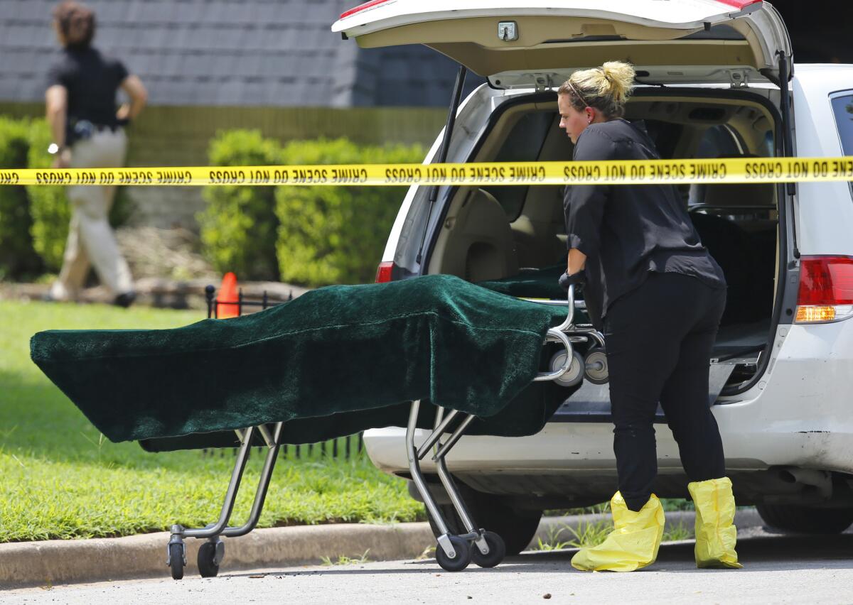 A worker wheels a body bag to a coroner's van outside the home in Broken Arrow where five family members were found stabbed to death.