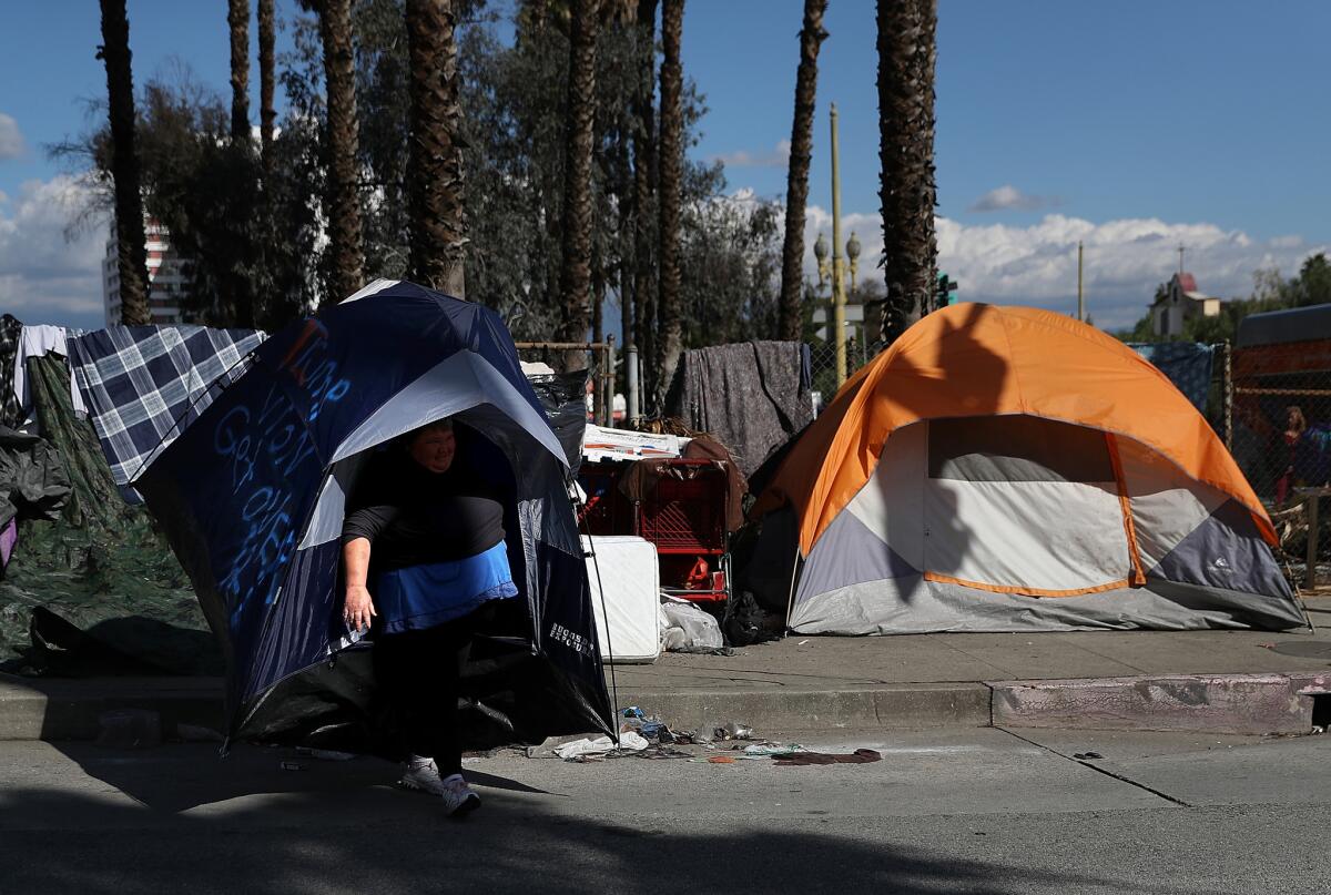 A homeless woman in Los Angeles carries her tent as she relocates her camp in January. County voters will decide on a sales tax measure to reduce homelessness.