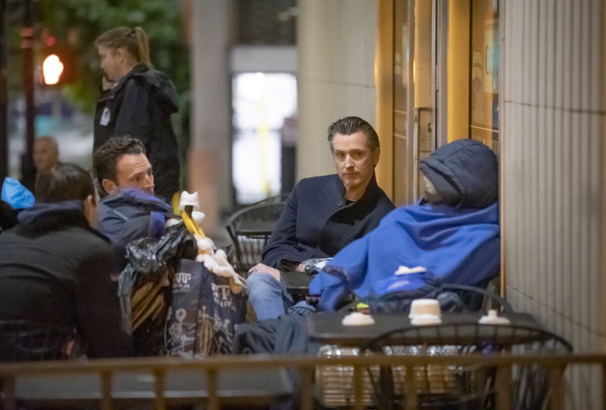 California Gov. Gavin Newsom , center, along with county Supervisor Nathan Fletcher, left, talk with a homeless man named Eric outside City Hall during an annual count of homeless people Jan. 23.