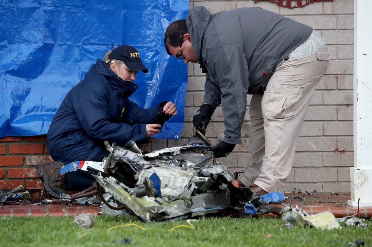 Maja Smith, left, National Transportation Safety Board investigator, and air safety investigator Ricardo Asensio inspect pieces of the wreckage after the February crash.