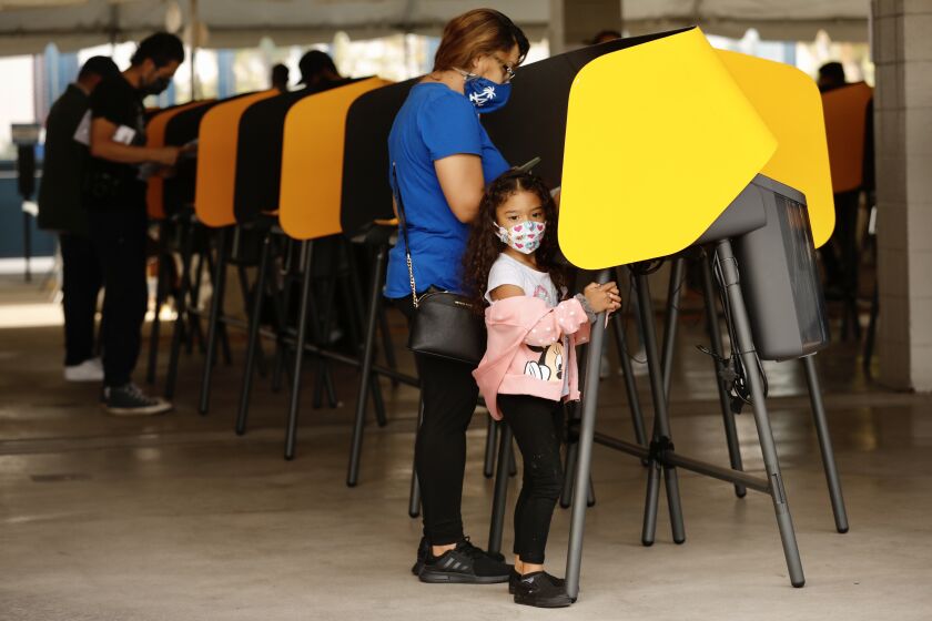 Arabella Abarca, 4 years old waits patiently as her mom Alexis Abarca votes at Dodgers stadium.