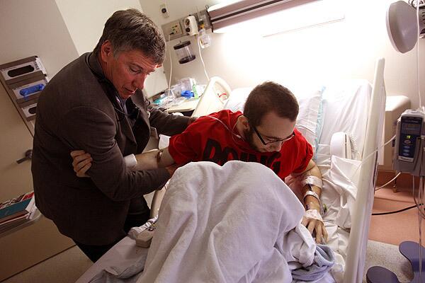 Dr. Michael Lill helps patient Kyle Hester, 21, a Jehovah's Witness from Fresno, sit up before examining him in his hospital bed. Hester is awaiting a stem cell transplant.