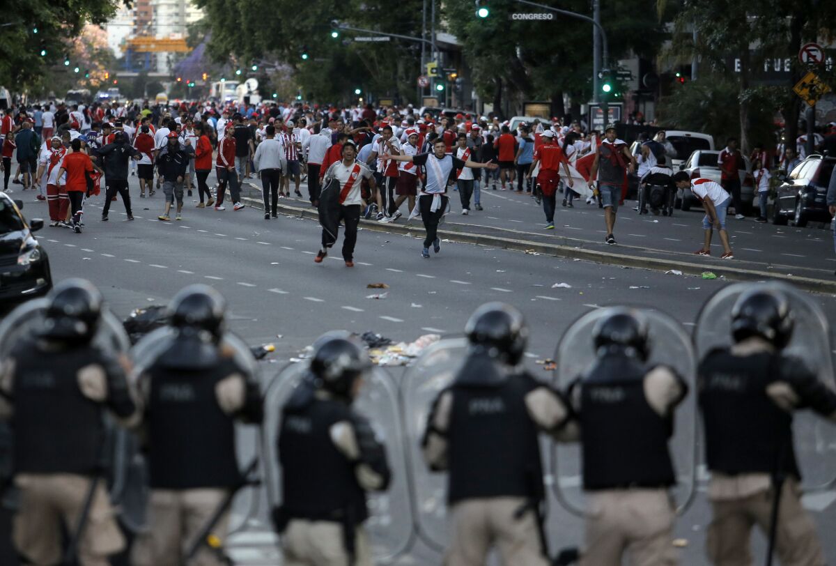 In this Saturday, Nov. 24, 2018 photo, Argentina River Plate fans clash with riot police outside the Antonio Vespucio Liberti stadium prior the final soccer match of the Copa Libertadores between River Plate and Boca Juniors, in Buenos Aires, Argentina. The match has been rescheduled after the bus carrying the Boca Juniors players was attacked by River Plate fans, injuring several players. The match will be played on Sunday.