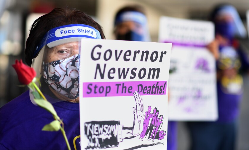 An LAX employee holds a sign calling on Gov. Newsom to "stop the deaths" 