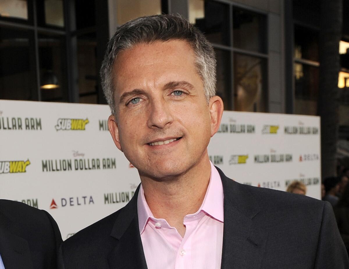 Bill Simmons in a black suit jacket and a pink suit shirt smiling