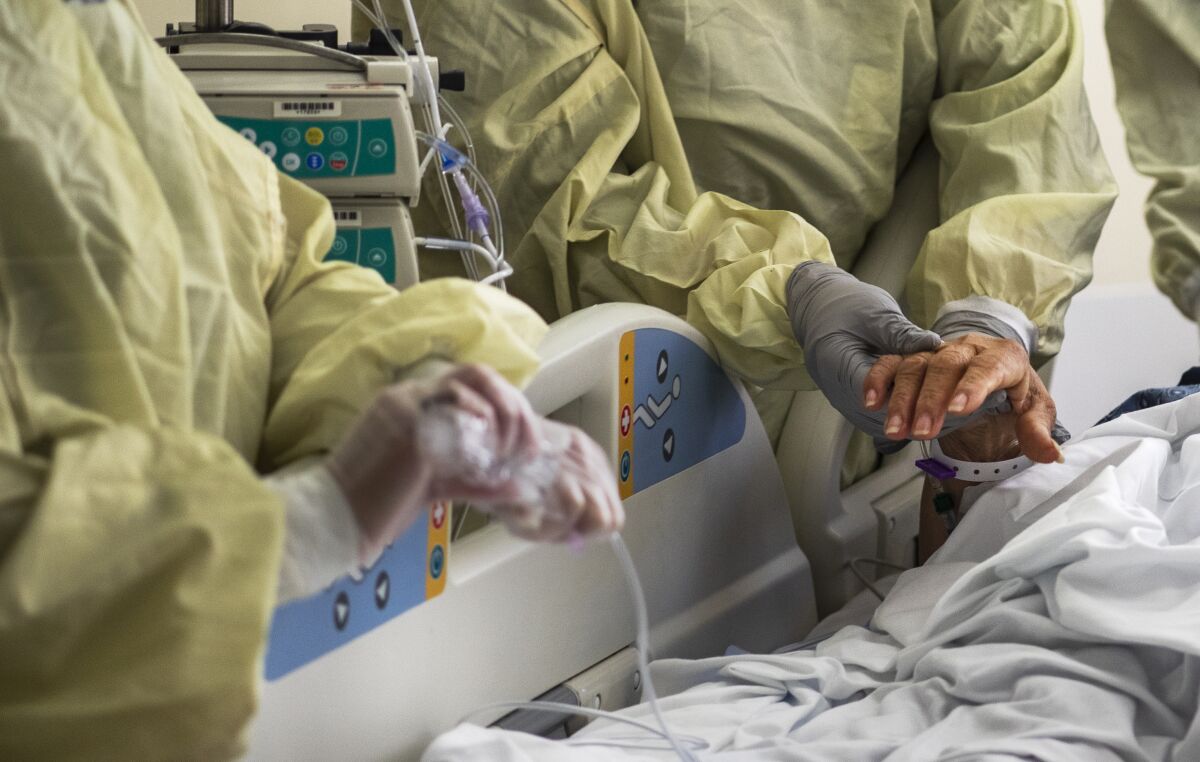 A nurse holds a COVID-19 patient's hand before she is intubated in the ICU at Loma Linda University Medical Center on Dec. 15