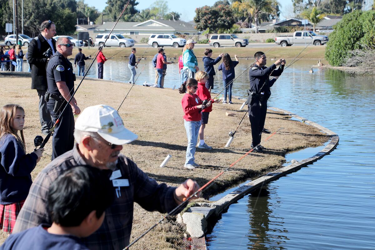 Volunteers help fifth-graders during the "Fish with the Force" event Friday at Carr Park in Huntington Beach. 