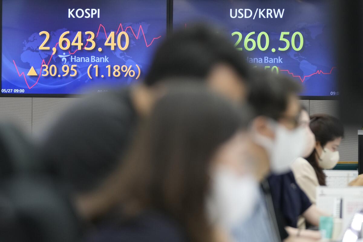 Currency traders watch computer monitors near the screens showing the Korea Composite Stock Price Index (KOSPI), left, and the foreign exchange rate between U.S. dollar and South Korean won at a foreign exchange dealing room in Seoul, South Korea, Friday, May 27, 2022. Asian shares gained Friday as investors cheered a strong set of earnings from retailers that has sent U.S. shares higher. (AP Photo/Lee Jin-man)
