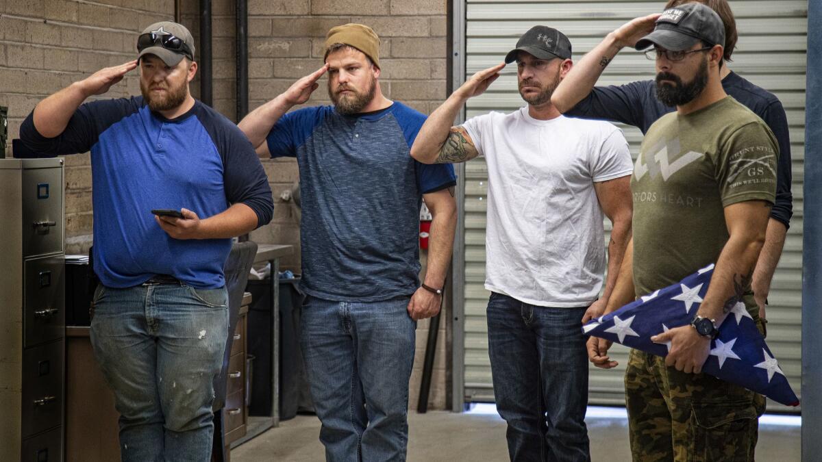 Friends and former volunteer fighters salute the casket of their friend Kevin Howard as it's prepared for cremation.