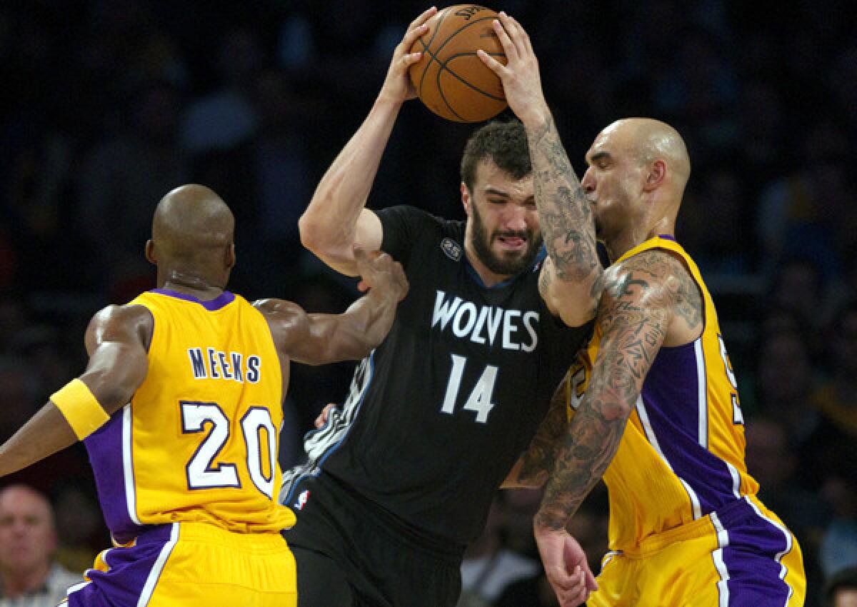 Lakers guard Jodie Meeks tries to help center Robert Sacre stop a driving by Timberwolves center Nikola Pekovic (14) in the first half Friday night at Staples Center.
