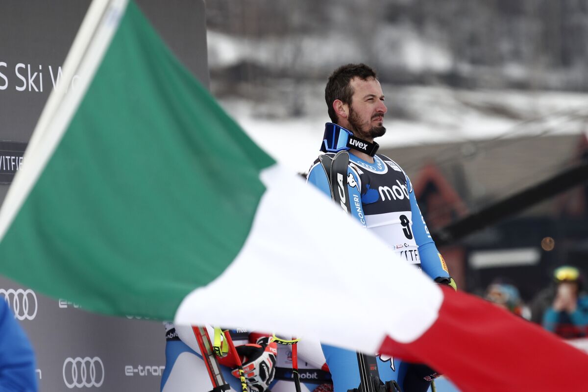 Italy's Dominik Paris is framed by an Italian flag as he stands on the podium after winning an alpine ski, World Cup men's downhill in Kvitfjell, Norway, Saturday, March 5, 2022. (AP Photo/Gabriele Facciotti)