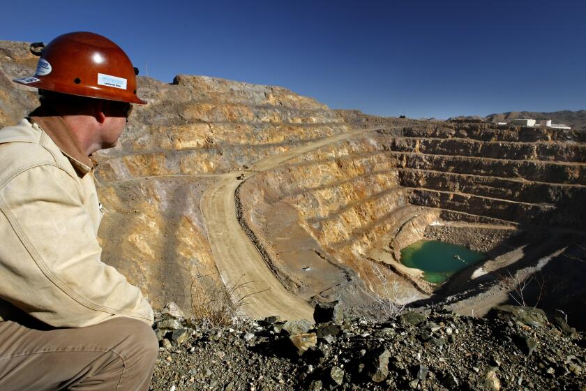 Environmental manager Scott Honan gazes across a 400-foot-deep Molycorp rare-earth mine in Mountain Pass, Calif. The open pit off I-15 near the California-Nevada border will be widened and deepened to harvest rare-earth elements that are in demand for products such as electric car and wind turbine batteries. (Don Bartletti / Los Angeles Times)