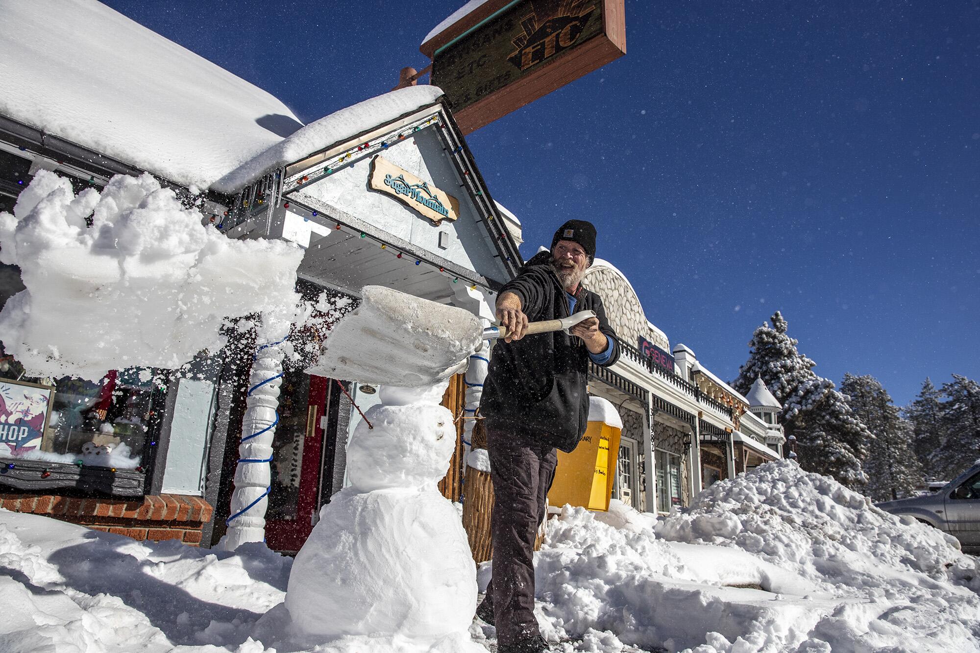 Store owner Adam Hurlbut shovels snow from in front of Sugar Mountain gift store in Running Springs, Calif.