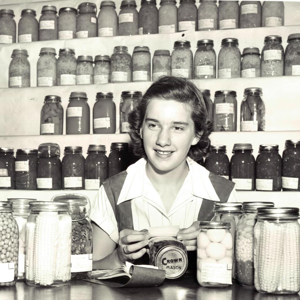 Barbara Smith puts labels on canned goods in a foods exhibit at the 1951 state fair.