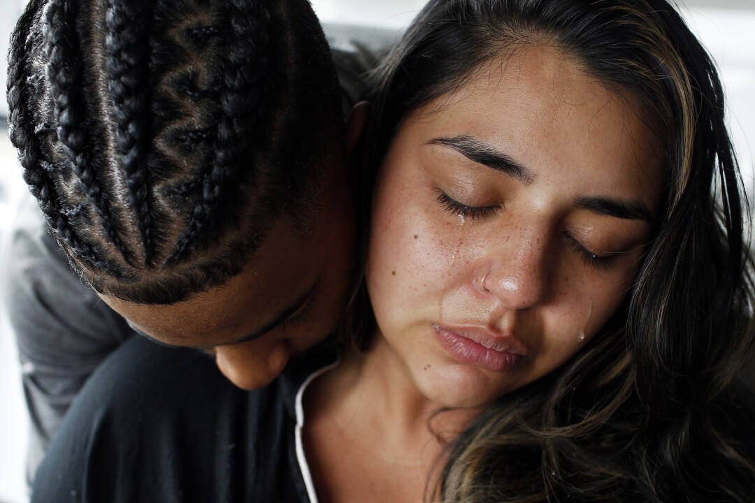 Gladys Sanchez cries while her partner rests his chin on her shoulder