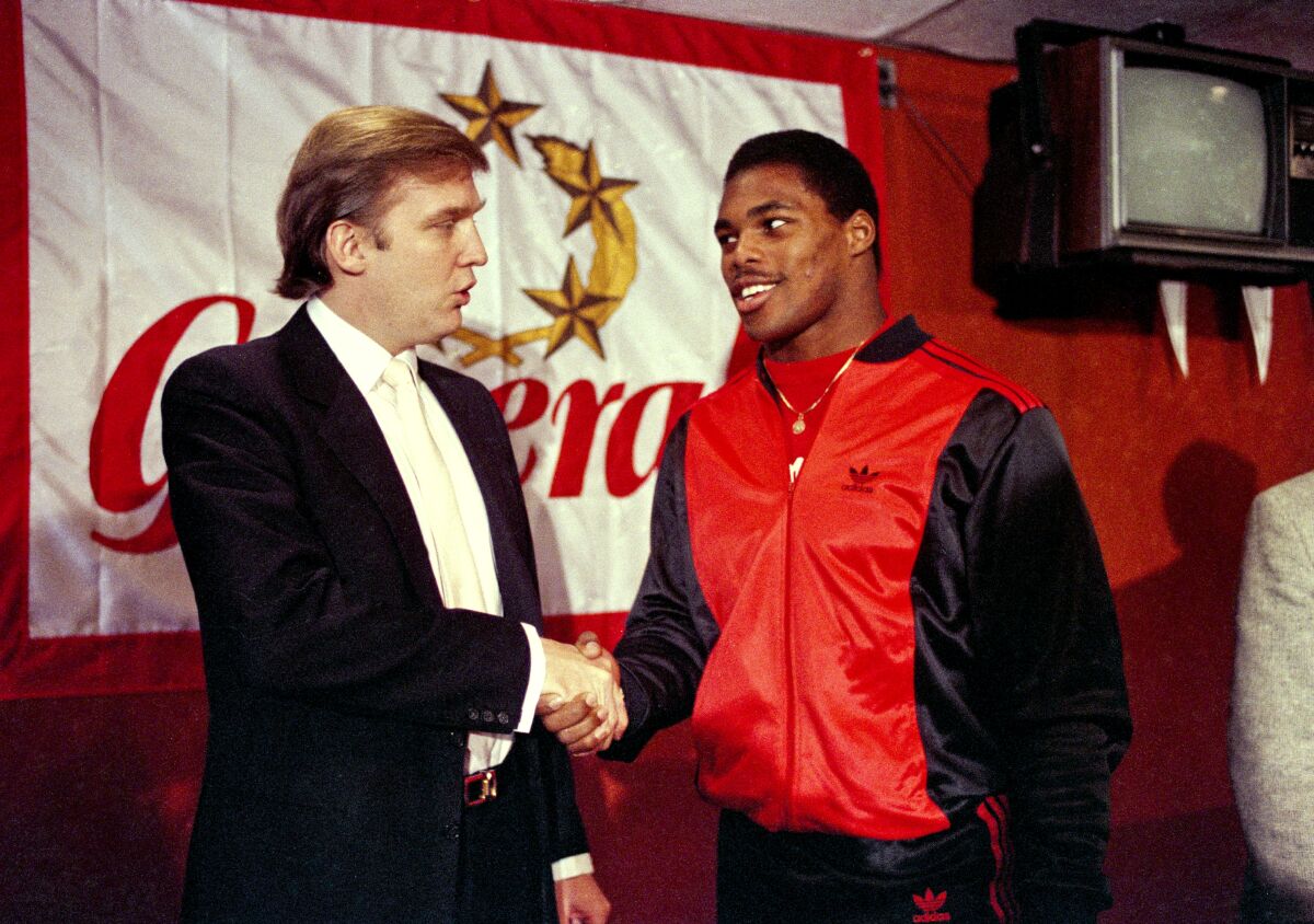 Donald Trump, then-New Jersey Generals owner, shakes hands with Herschel Walker at a press event on March 8, 1984.