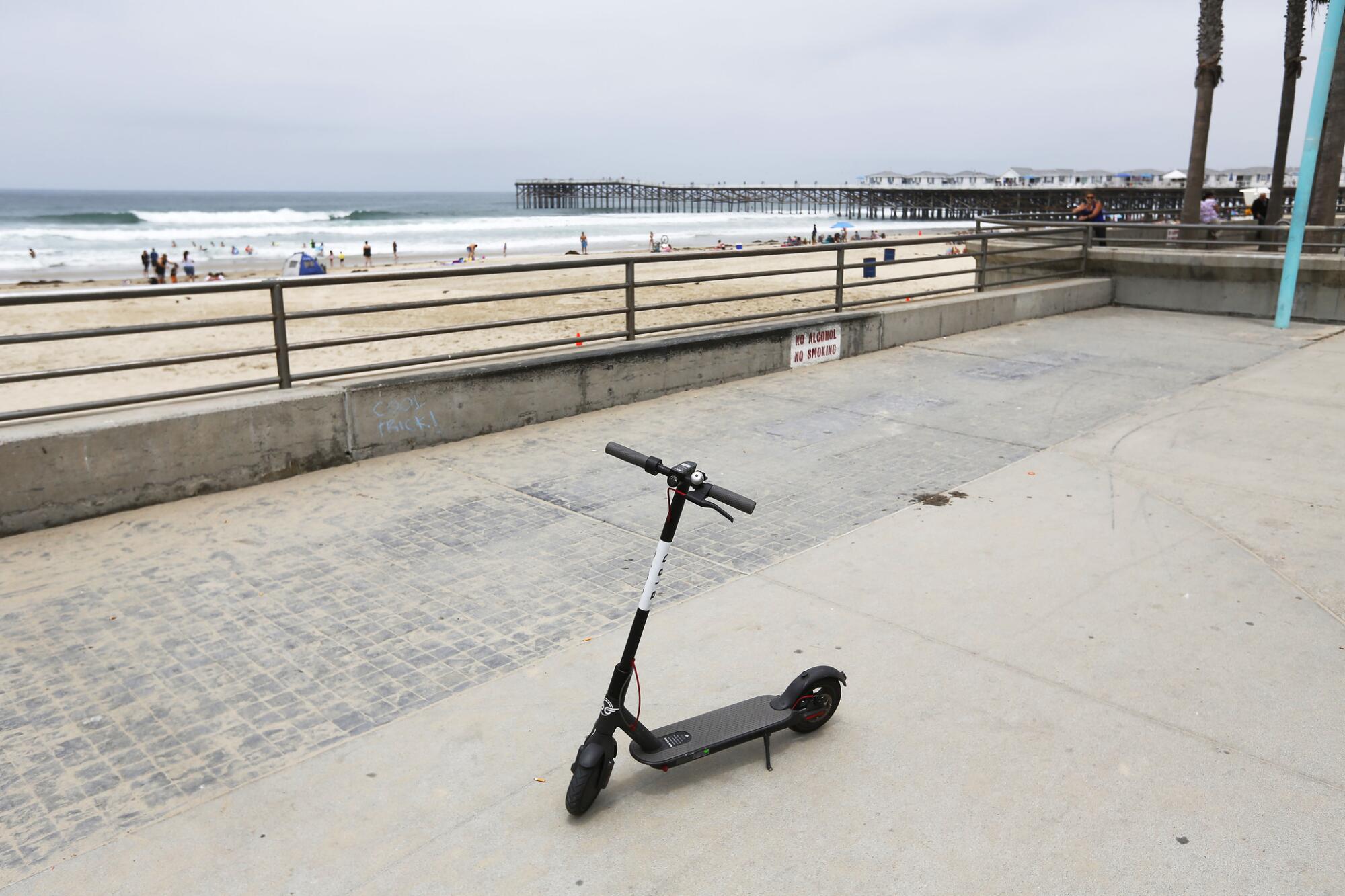 A Bird Scooter is parked on the boardwalk in Pacific Beach.