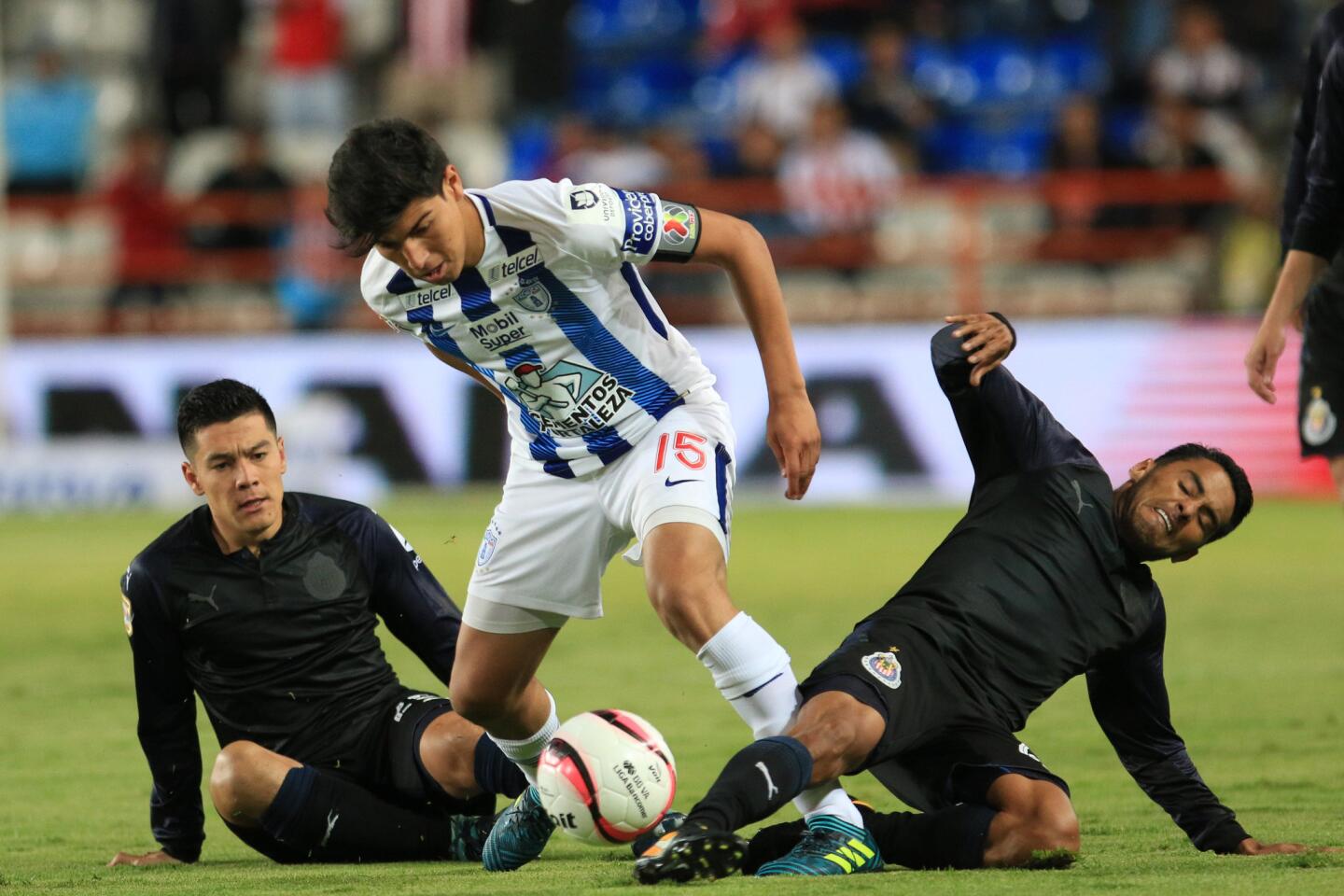 Erick Aguirre de Pachuca (c) disputa el balón con Michael Perez (i) y José Vazquez (d) del Guadalajara, que lució uniforme negro en lugar del tradicional rojiblanco.