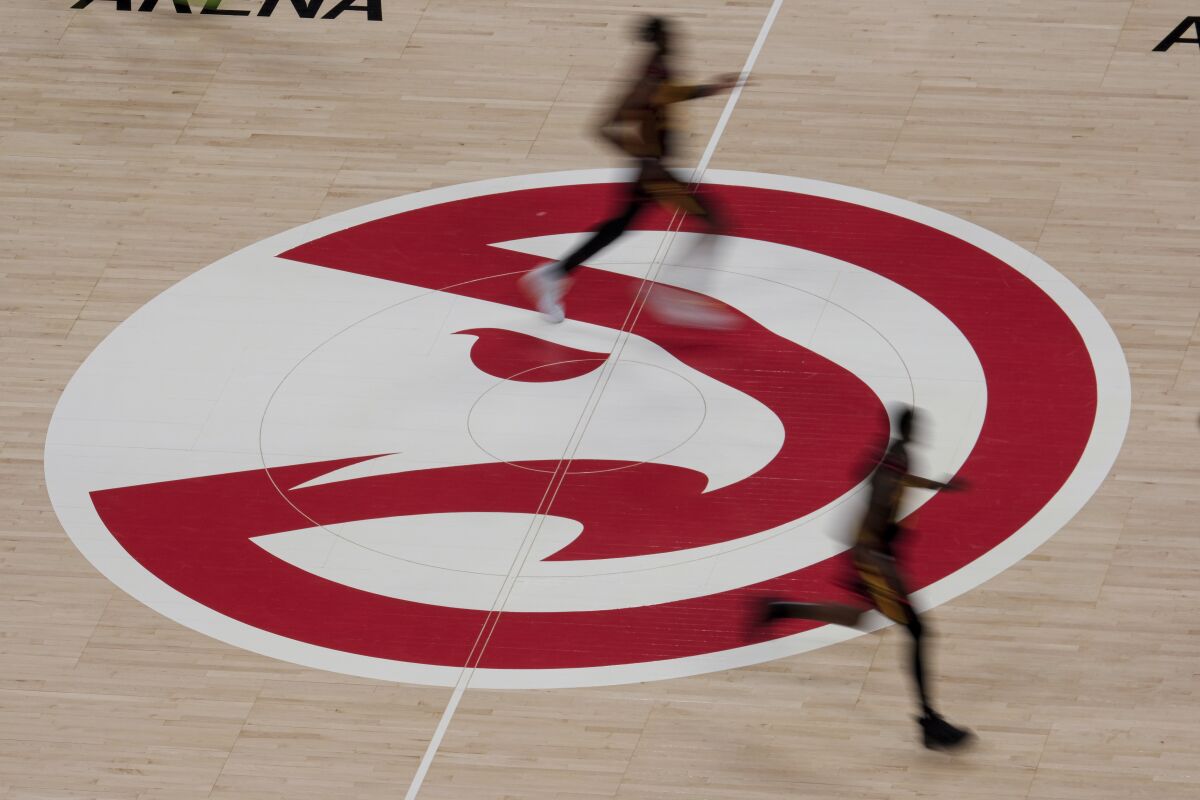 Atlanta Hawks players run past the Hawks logo during the second half of an NBA basketball game against the Houston Rockets on Sunday, May 16, 2021, in Atlanta. (AP Photo/Ben Gray)