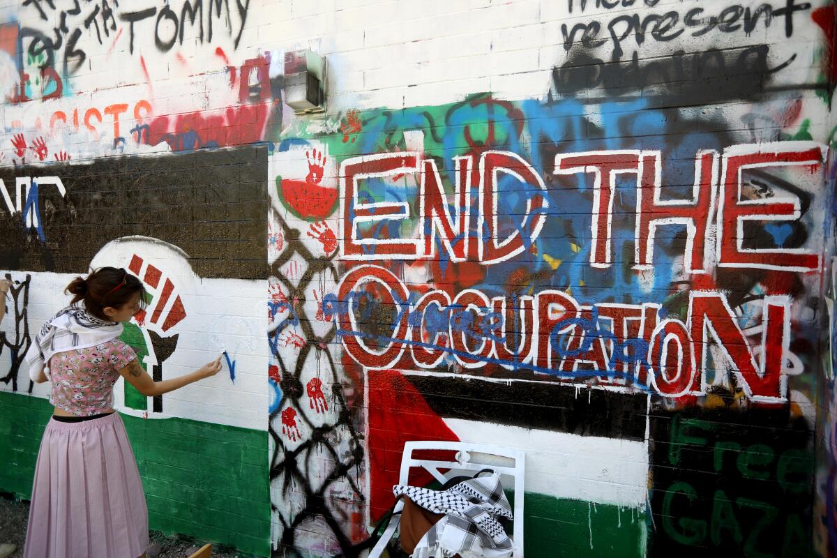 A protesters paints part of a pro-Palestinian mural