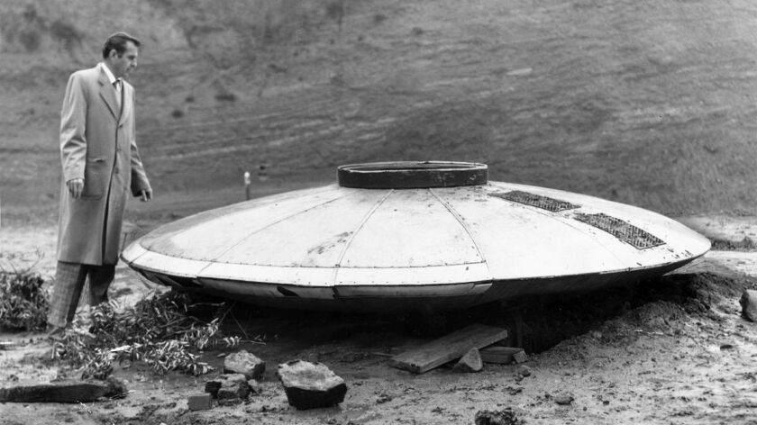 Times reporter Dewey Linz inspects a faux UFO that turned up in the Hollywood Hills in 1957.