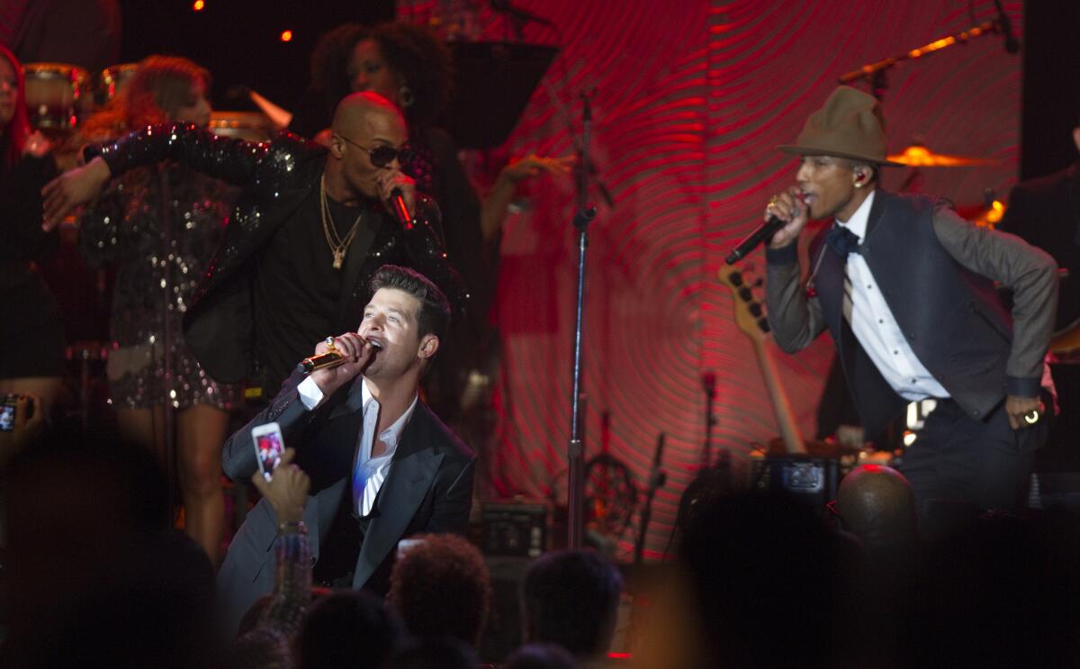Robin Thicke, front, performs with Pharrell Williams, right, during the 2014 Pre-Grammy gala at the Beverly Hilton.