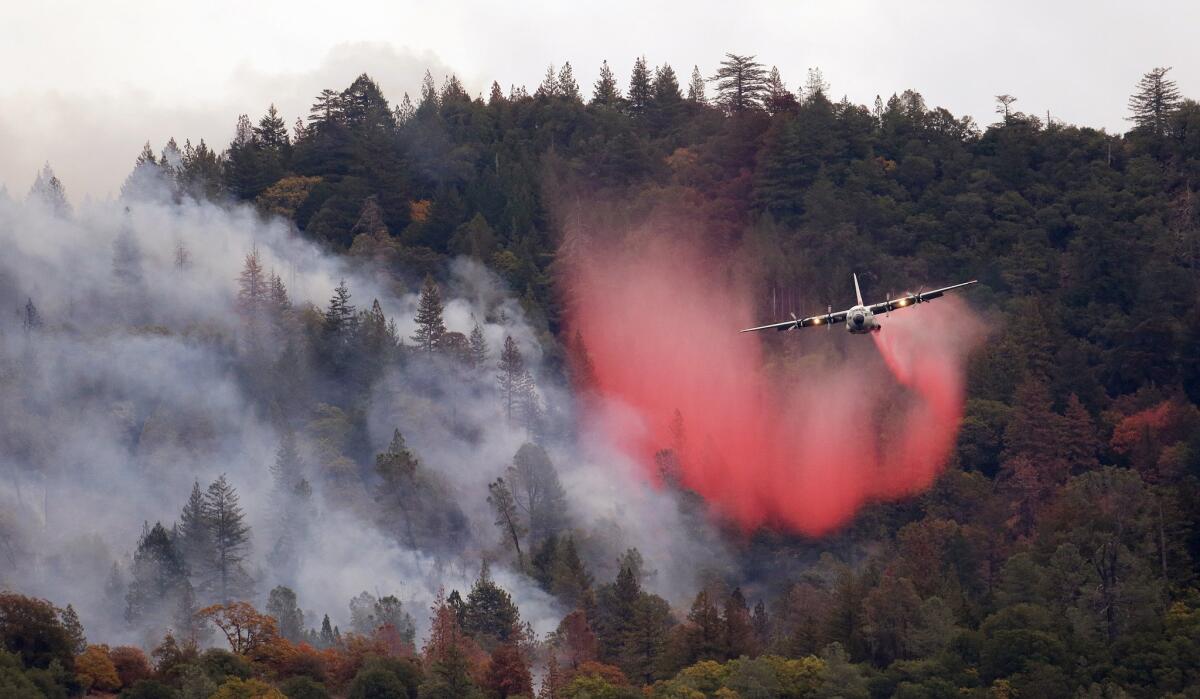In this Sept. 15, 2015, file photo, a plane drops a load of fire retardant over a smoldering hillside in Middletown, Calif. Thanks to El Niño rains, the risk of wildfires has diminished.