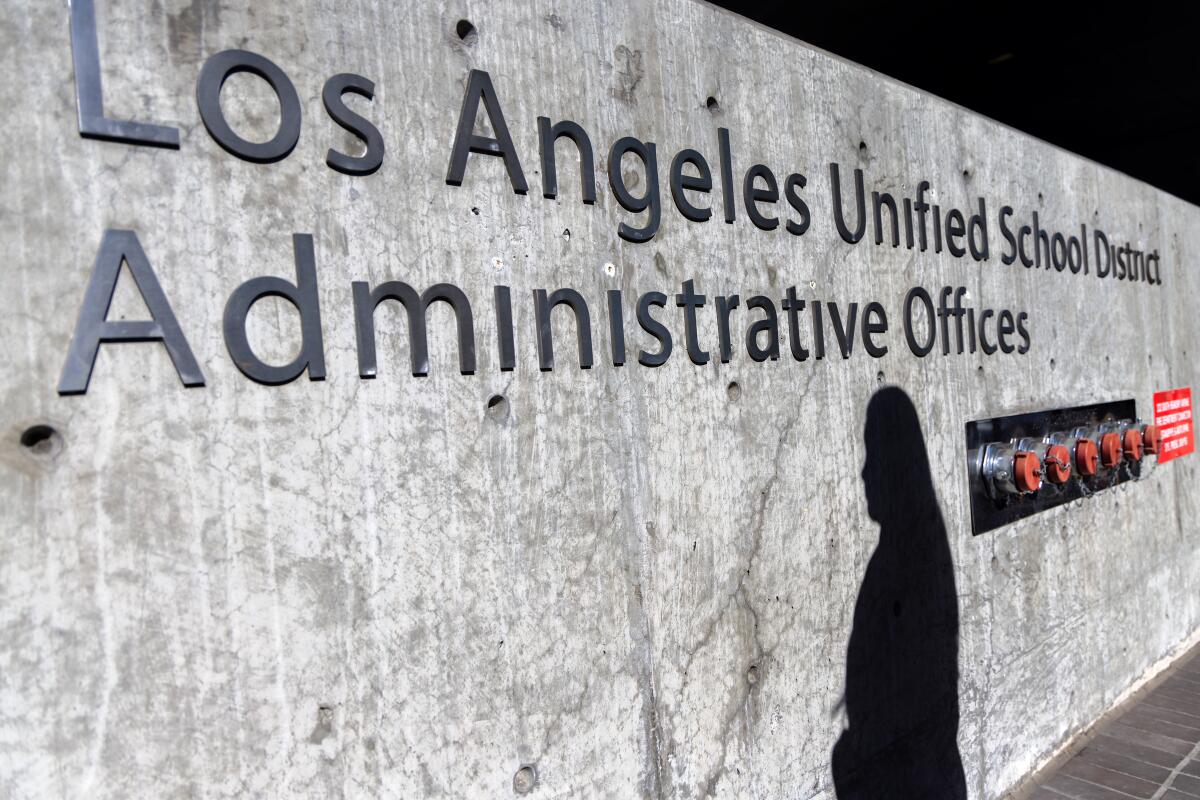 A woman's shadow falls on a sign outside L.A. Unified's headquarters in Los Angeles.