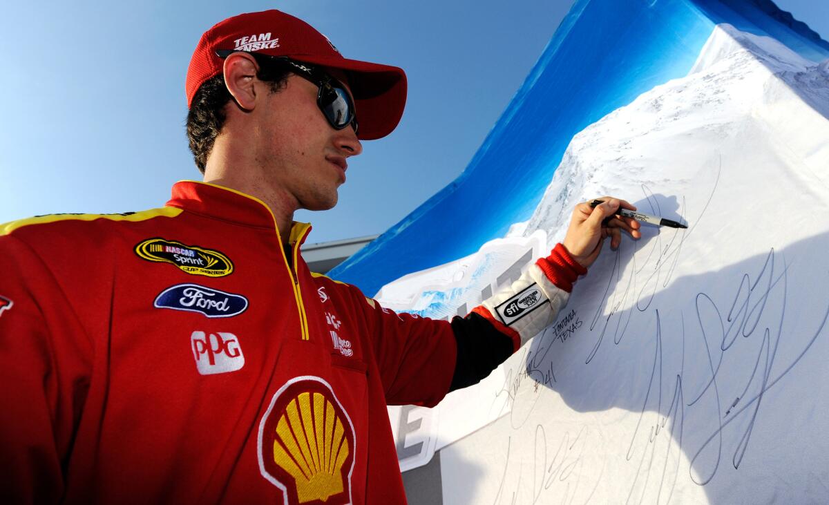 Joey Logano signs a poster Friday after winning the pole for the Toyota Owners 400 at Richmond International Raceway.