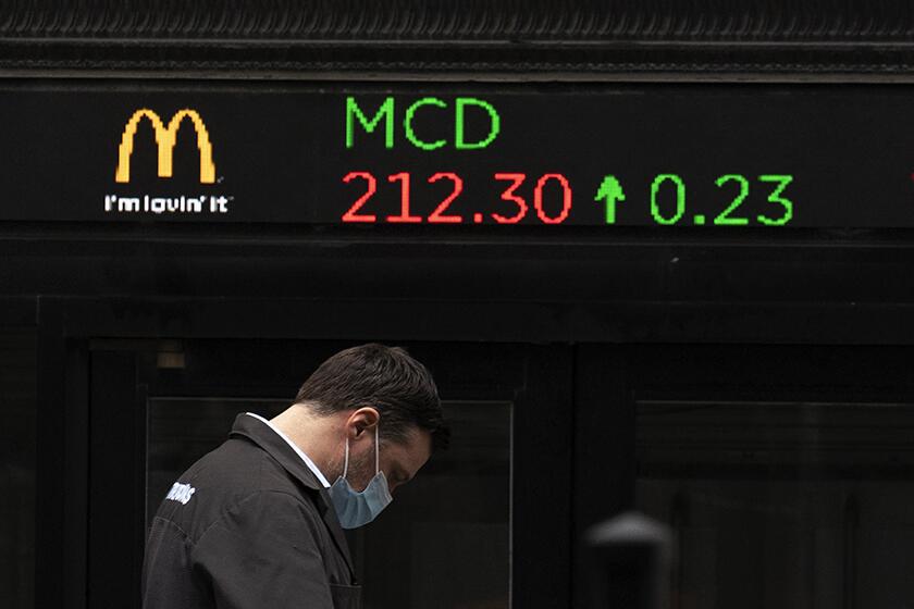 A man walks past a stock ticker at the New York Stock Exchange.