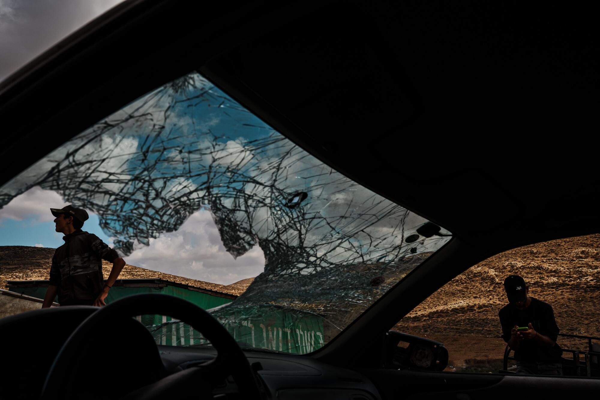 Palestinian boys inspect the windshield of a vehicle that was damaged by settlers who stoned it.