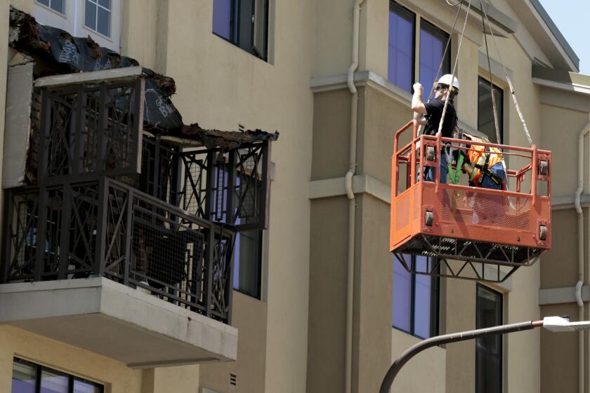 Workers examine a balcony that collapsed at an apartment building in Berkeley.