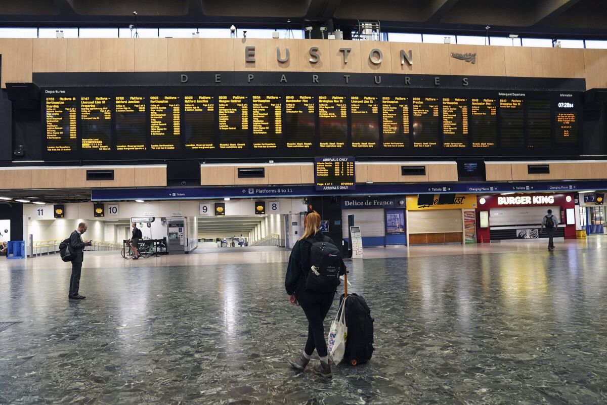 Passengers stand on a deserted London Euston train station, in London, Thursday Aug. 18, 2022. Rail services are set to be severely disrupted as members of the Transport Salaried Staffs Association (TSSA) and the Rail, Maritime and Transport (RMT) union strike in a continuing row over pay, jobs and conditions. (Stefan Rousseau/PA via AP)