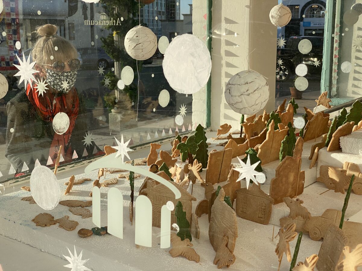 A passerby looks at the Athenaeum's cookie village display.