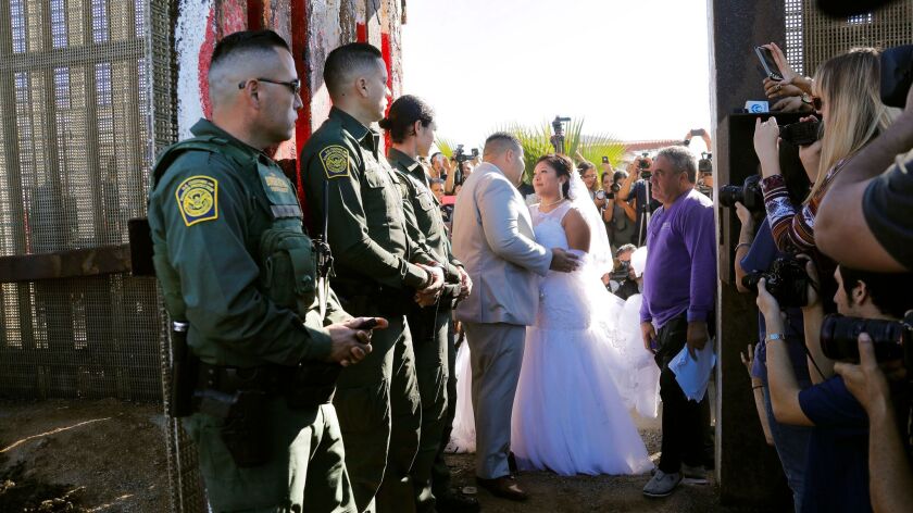 Brian Houston of Rancho San Diego, left, and Evelia Reyes, right, of Tijuana, are married at the "Door of Hope," part of the border fence inside Border Field State Park that was opened occasionally for families to temporarily reunite.