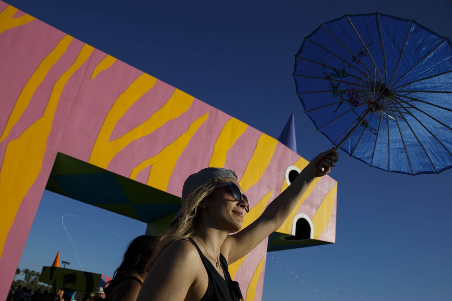 An attendee carries an umbrella while walking past the art project "is this what brings things into focus?" by Joanne Tatham and Tom O'Sullivan, during weekend one of the three-day Coachella Valley Music and Arts Festival at the Empire Polo Grounds on Friday, April 14, 2017 in Indio, Calif. (Patrick T. Fallon/ For The Los Angeles Times)