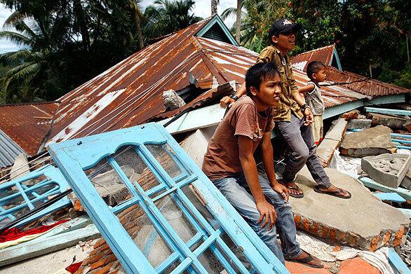 Villagers sit atop a house destroyed in the Sept. 30 earthquake that devastated a stretch of the western coast of Sumatra.