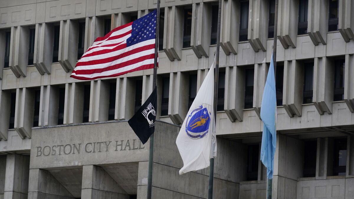 The American flag, the Commonwealth of Massachusetts flag, and the City of Boston flag fly outside Boston City Hall.