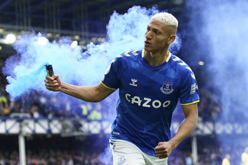 FILE - Everton's Richarlison runs with a flare as he celebrates after scoring his sides first goal during the Premier League soccer match between Everton and Chelsea at Goodison Park in Liverpool, England, on May 1, 2022. Tottenham forward Richarlison has been banned from his new club’s Premier League opening game after throwing a smoke canister when playing for Everton last season. The English Football Association says Richarlison admitted a charge of improper conduct. He's been banned for one game and fined $30,000. (AP Photo/Jon Super)