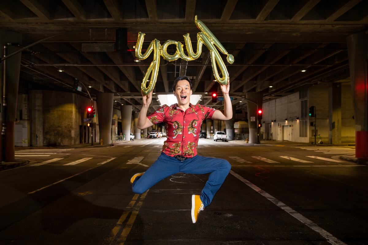 Comedian Aidan Park jumps in the middle of a downtown L.A. street holding a "Yay" balloon