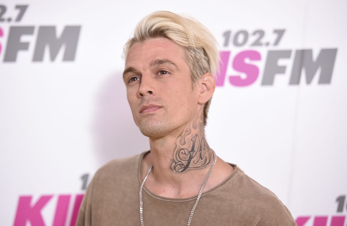 A blond man with a neck tattoo looks up.