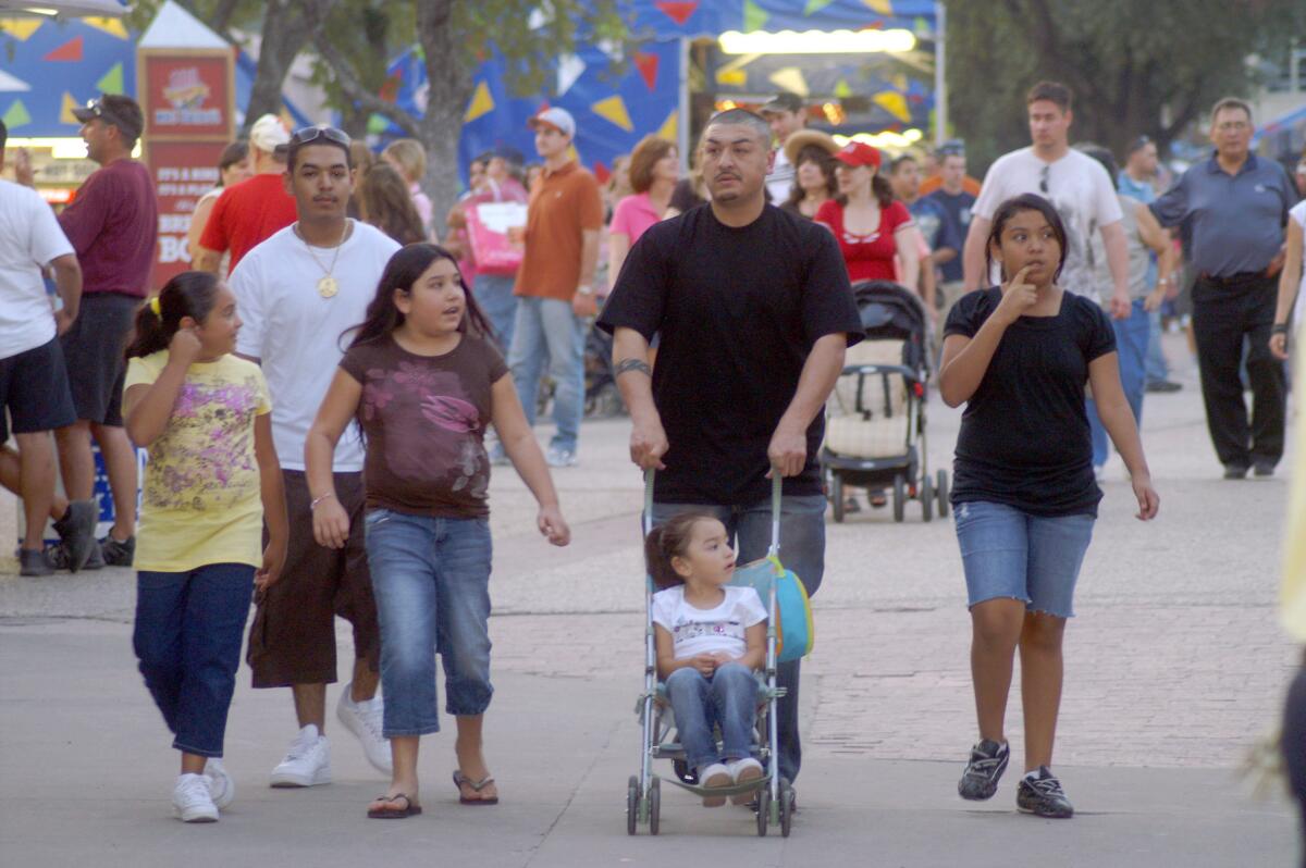 Una familia hispana pasea por las instalaciones de la Feria Estatal de Texas, en Dallas, a la que cada año acuden más de tres millones de personas.